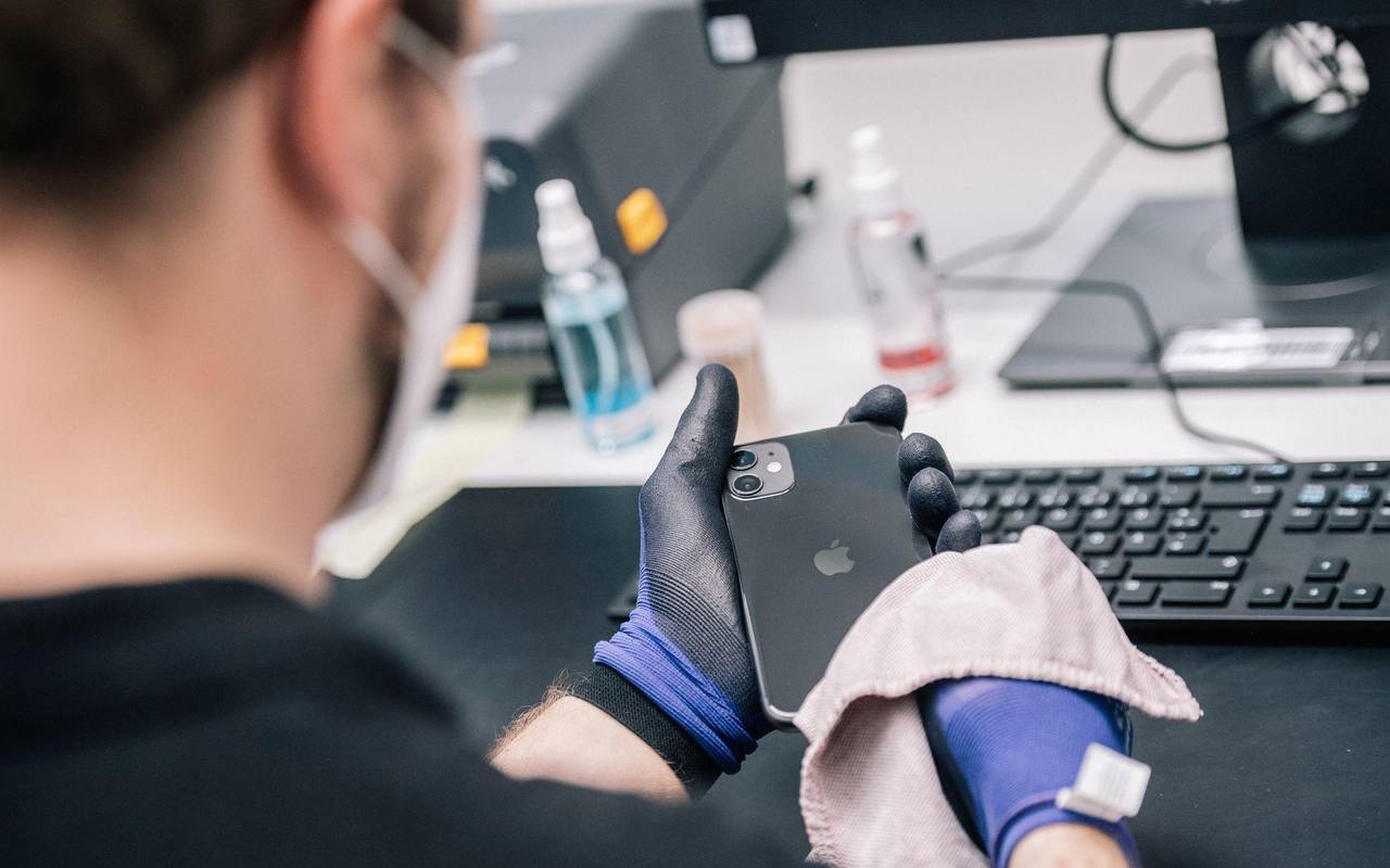Ein Mitarbeiter überprüft ein refurbished Iphone